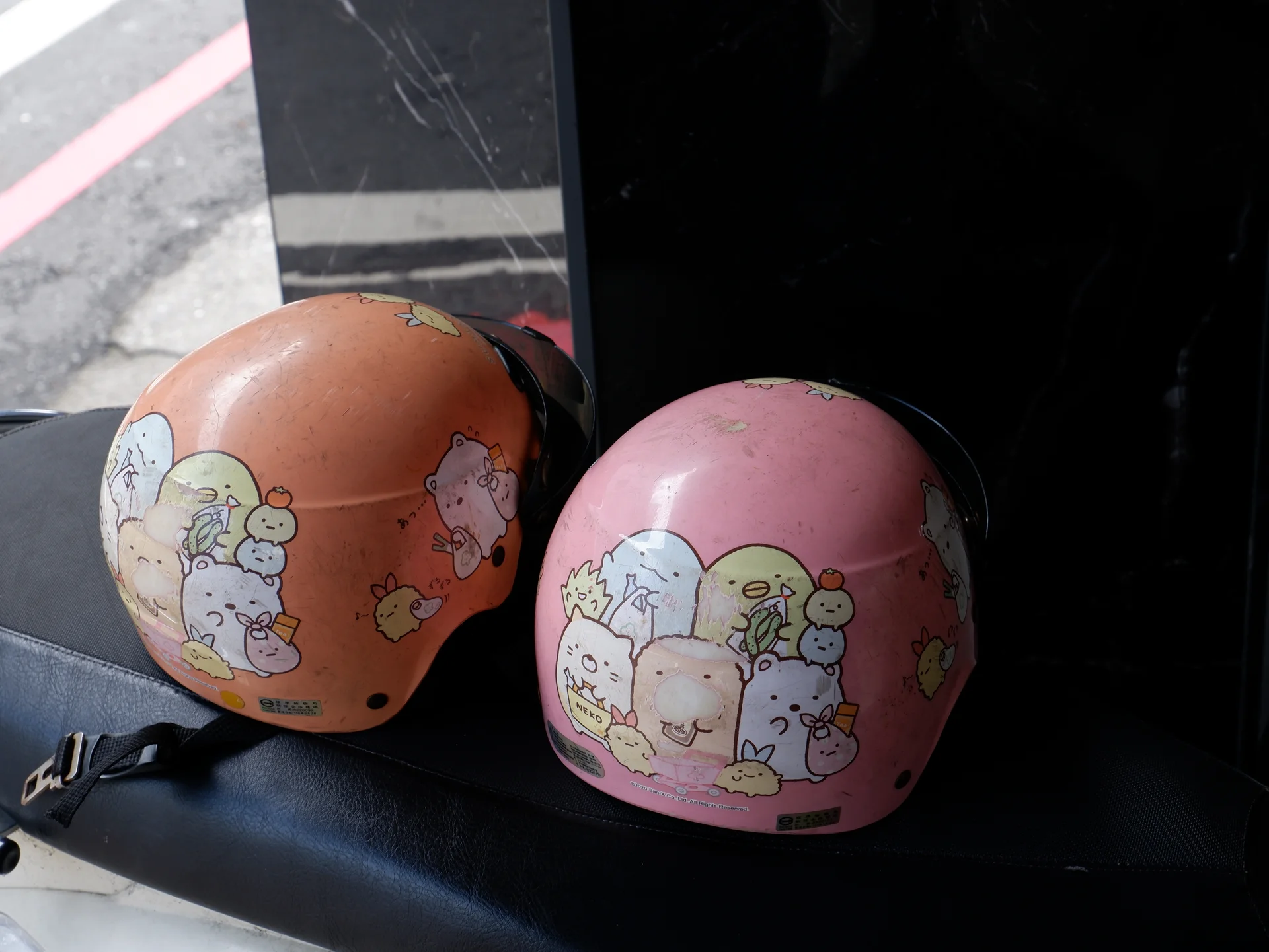 Two illustrated helmets on a scooter seat